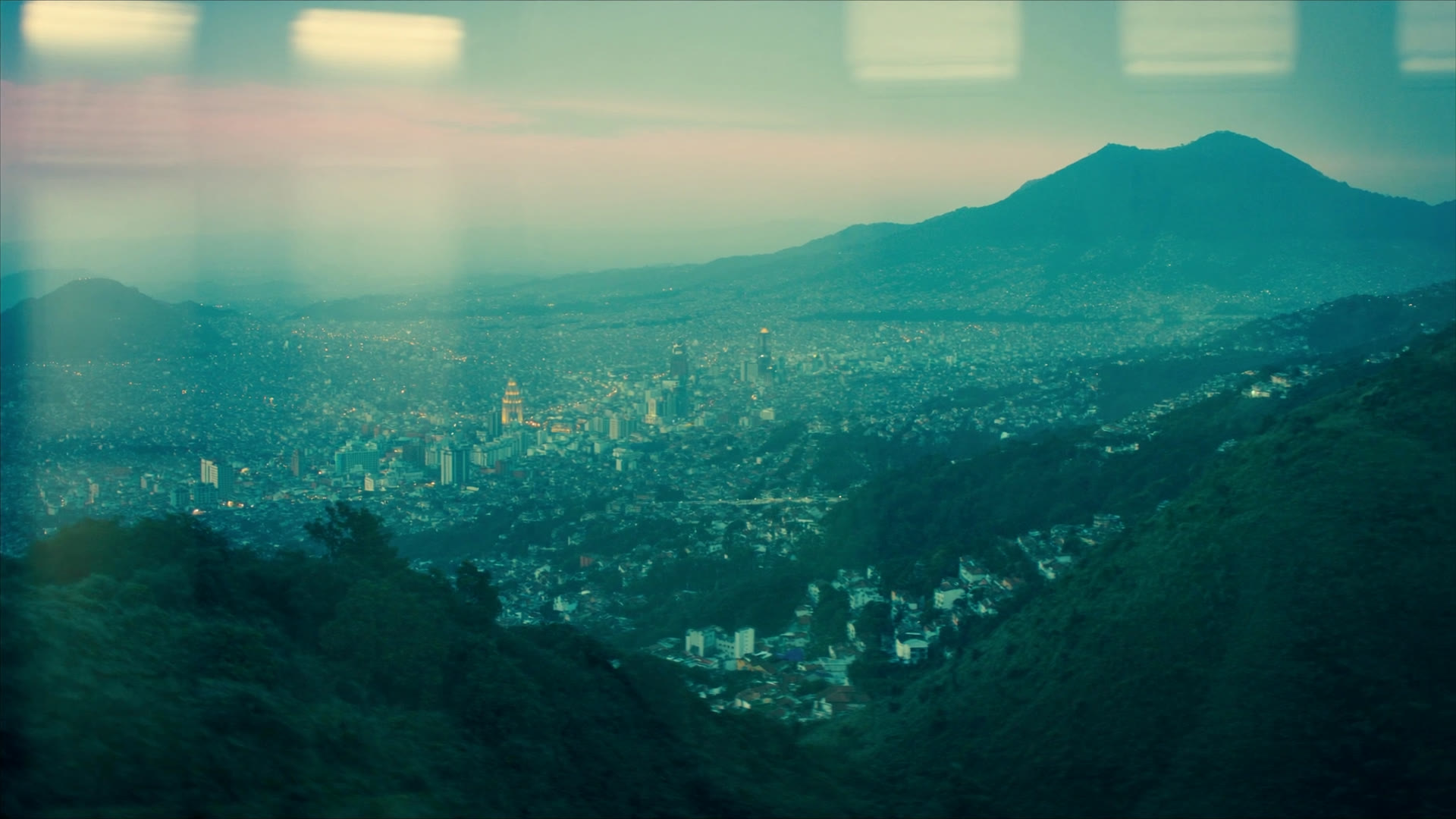 A Latin American city in a valley at dusk, ringed by mountains